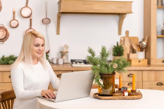 Smiling woman sitting surfing the internet on a laptop computer at home,