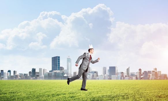 Young handsome businessman wearing white paper crown running in a hurry