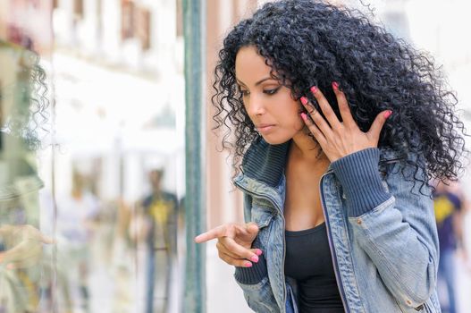 Portrait of an attractive black woman, afro hairstyle, looking at the shop window