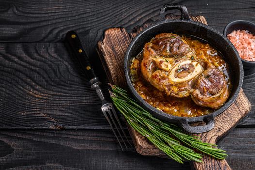 Stew veal shank meat OssoBuco, italian osso buco steak. Black wooden background. Top view.