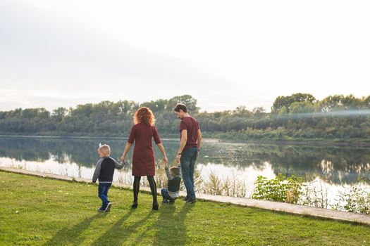 Parent, childhood and nature concept - Family playing with two sons by the water.