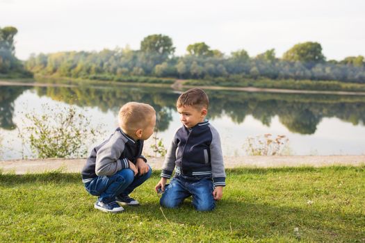 Children and nature concept - Two brothers sitting on the grass over nature background.