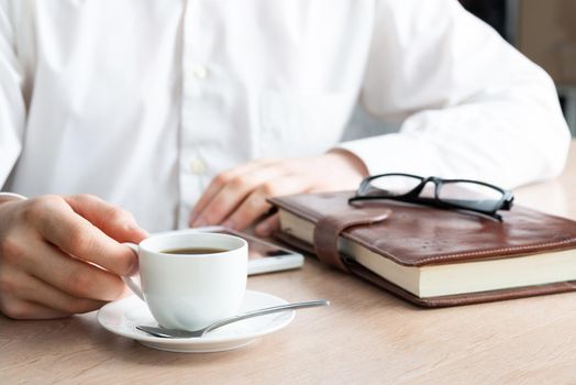 Businessman surfing internet on smartphone as sit in cafe with cup of coffee. Financial specialist working with online analytics. Business application and mobile technology. Internet communication