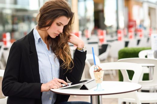Portrait of a woman looking at her tablet computer, sitting in a coffee shop