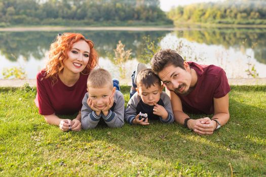 Children, parenthood and nature concept - Big family lying on the grass.