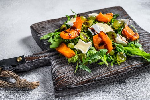 Autumn salad with baked pumpkin and brie cheese. Healthy vegan food concept. White background. Top view.