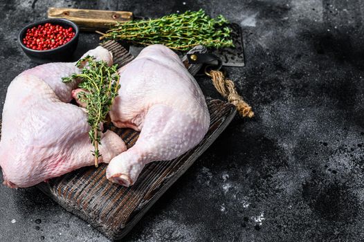 Fresh raw chicken legs on a cutting board. Black background. Top view. Copy space.