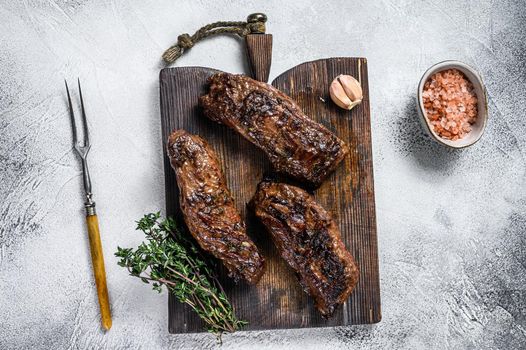 Grilled brisket steaks in bbq sauce on a wooden board. White background. Top view.
