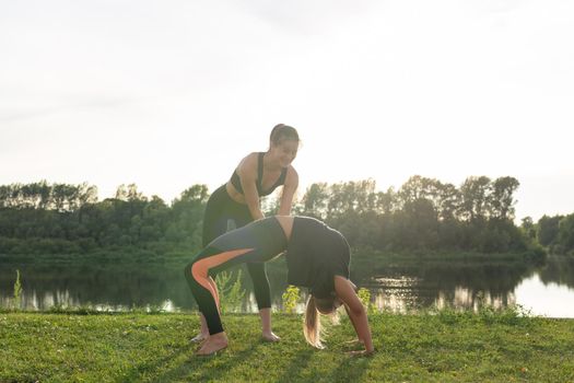 Healthy lifestyle and harmony concept - Young girls doing yoga outdoor.