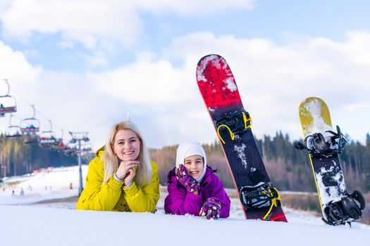 mother and daughter with snowboards at winter resort