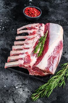 Raw fresh rack of lamb meat on marble board. Black background. Top view.