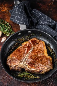 Grilled porterhouse beef meat Steak with herbs in a pan. Dark background. Top view.
