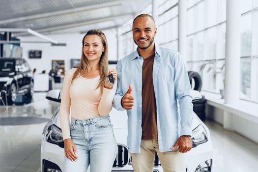 Happy excited couple or family buying a new car and showing keys