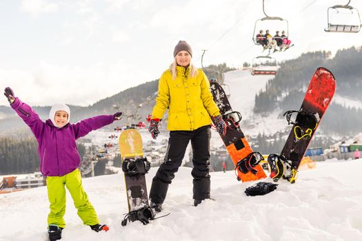 mother and daughter with snowboards at winter resort