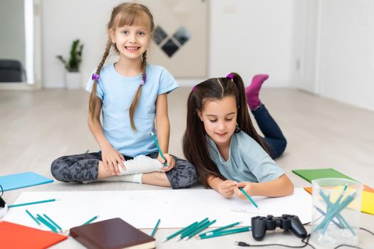 Cute children are painting and smiling while lying on the floor at home