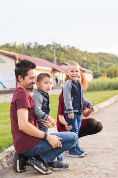 Parenthood, childhood and family concept - Parents and two male children walking at the park and looking on something.