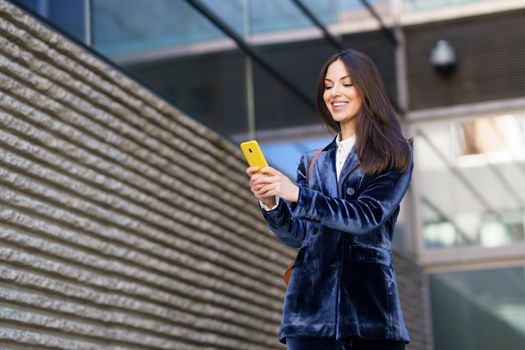 Business woman wearing blue suit using smartphone in an office building. Lifestyle concept.