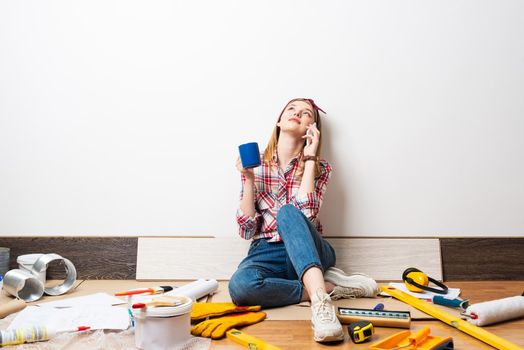 Dreamy girl talking on smartphone at home. Apartment remodeling and house interior renovation concept with copy space.