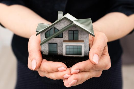 woman hands holding paper house, model.