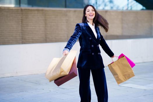 Caucasian woman turning with joy for her purchases in shopping bags. Lifestyle concept.
