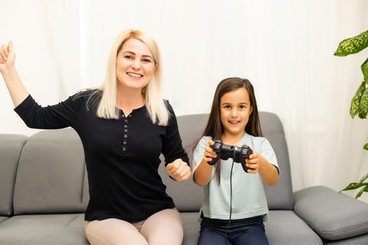 Mother and daughter sittingr in a playroom, playing video games and having fun.