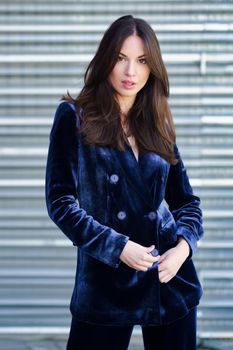 Woman wearing blue suit posing near a modern metal building. Lifestyle concept.