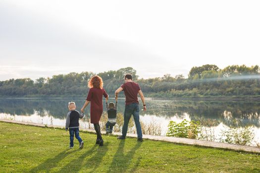 Parent, childhood and nature concept - Family playing with two sons by the water.