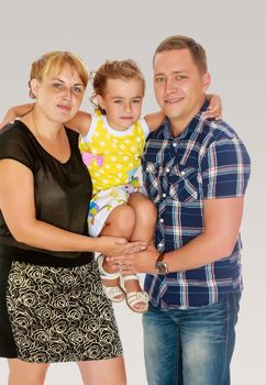 The parents are raised at the hands of his little daughter. And gently embrace her.On a gray background.