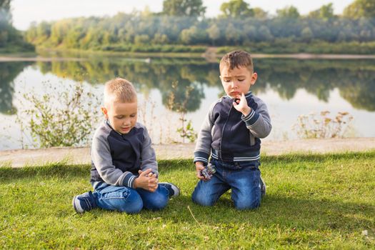 Children and nature concept - Two brothers sitting on the grass over nature background.