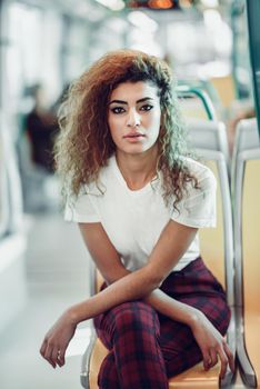 Arabic woman sitting inside subway train. Arab girl in casual clothes near a window.