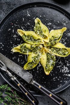 Italian Jumbo shells pasta Conchiglioni stuffed with beef meat and spinach on a plate. Black background. Top view.