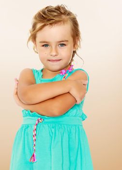 Pretty Little tanned girl in a smart blue dress. The girl folded her arms. Close-up.On a brown gradient background.