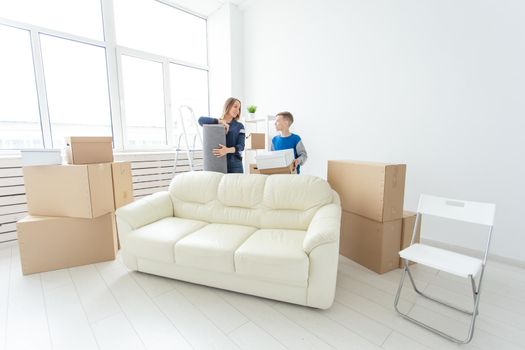 Young cute single mother and son are happy about the move to new house holding a pot of greens and carpet in their hands. Concept of housewarming and family space extensions