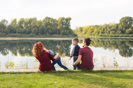 Childhood and nature concept - Family with little sons sitting on the green grass.