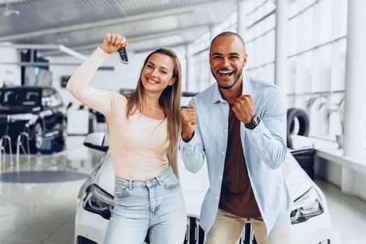 Happy excited couple or family buying a new car and showing keys