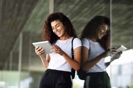 Happy young Arab woman using digital tablet in business background. Happy girl wearing sportswear.