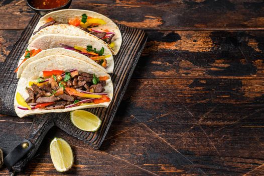 Tacos shells with pork meat, onion, tomato, sweet pepper and salsa. Mexican food. Dark wooden background. Top view. Copy space.