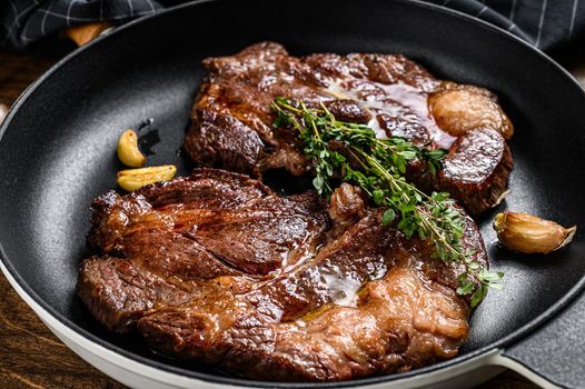 Roasted rib eye steaks in a pan. Dark wooden background. Top view.