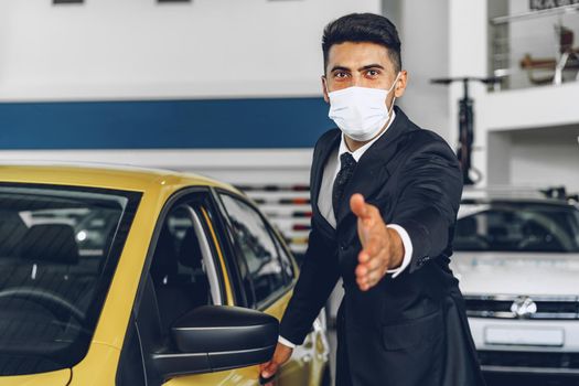 Man car dealer wearing protective medical mask on his working place, coronavirus prevention concept