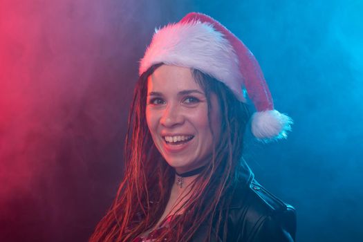 Rock, santa, people concept - emotional woman in santa hat shows tongue and rock.