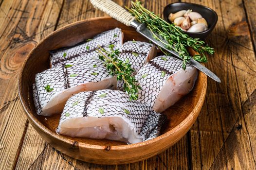 Cut Raw grenadier macrurus white fish without head in a wooden plate. Wooden background. Top view.