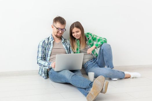 Charming young woman and a smiling man are watching online stores using a laptop to buy plumbing in a new apartment. Housewarming and repair concept. Copyspace