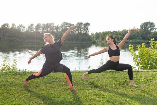 Small female fitness group doing yoga in park on a sunny day.