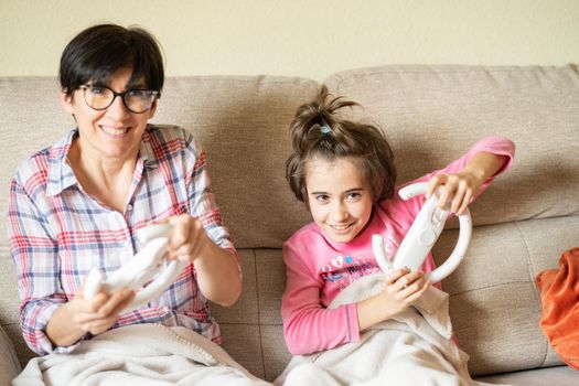 Mother and daughter playing video games at home with a wireless console