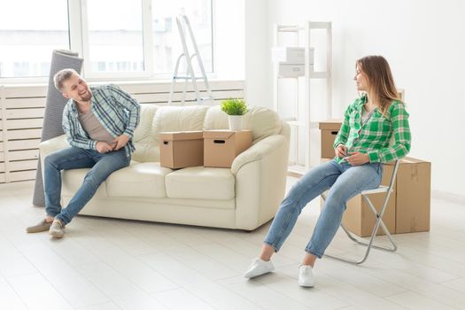 Positive smiling young girl sitting against her laughing in a new living room while moving to a new home. The concept of joy from the possibility of finding new housing