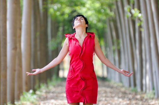 Woman dressed in red, meditating in the forest