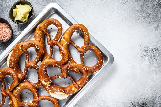 Salted pretzels with sea salt on a kitchen baking pan. White background. Top view. Copy space.