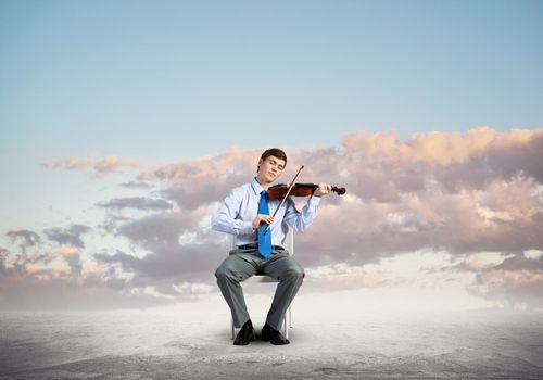 Young businessman plays the violin and enjoys the music. sits on a chair