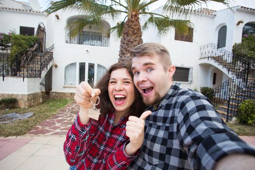 Property, real estate and rent concept - Happy smiling young couple showing a keys of their new house.