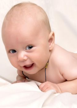 A charming baby lies on the blanket and looks into the camera. The concept of a happy childhood, the birth and upbringing of a child.